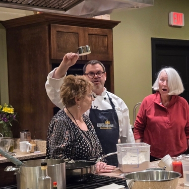 The chef demonstrates measuring a cup of flour with Kathryn