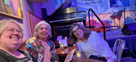 Barbara and friends smile together in front of the stage at Snug Harbor