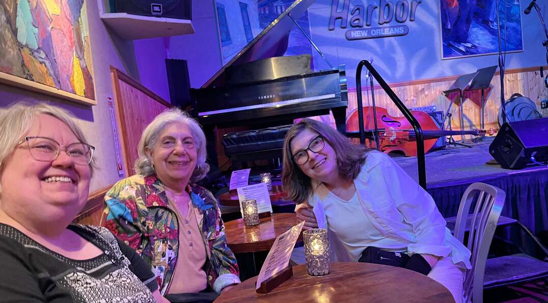 Barbara and friends smile together in front of the stage at Snug Harbor