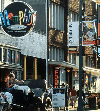 A vibrant Memphis street scene with neon signs for blues clubs, shops, and a horse-drawn carriage in the foreground.