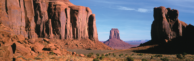 Massive red sandstone mesas and buttes rise from the desert floor in Monument Valley on Navajo lands in Arizona.
