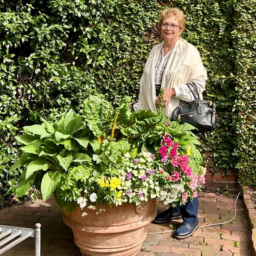 Kathryn smiles in front of hedges and flowers