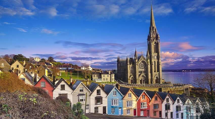 Colorful houses stand in a line in front of a church