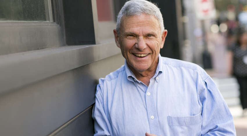 Mike Zoob smiles at the camera while leaning against a building